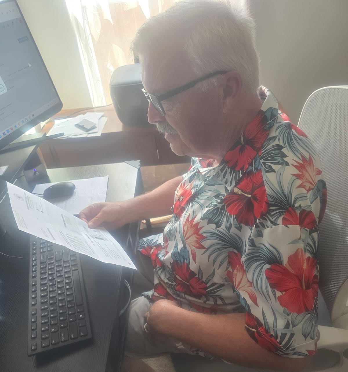 David Westgate reviewing a printed financial report at his desk in Conroe, Texas